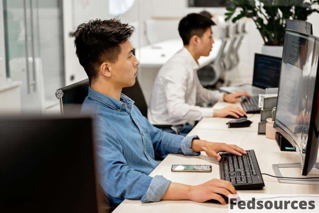 Young professionals working on computers in a modern office environment, focused on their tasks.